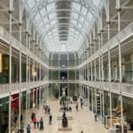 Spacious interior of the National Museum of Scotland in Edinburgh, showcasing its grand architecture and visitors.