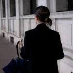 a woman walking down a street holding a blue umbrella