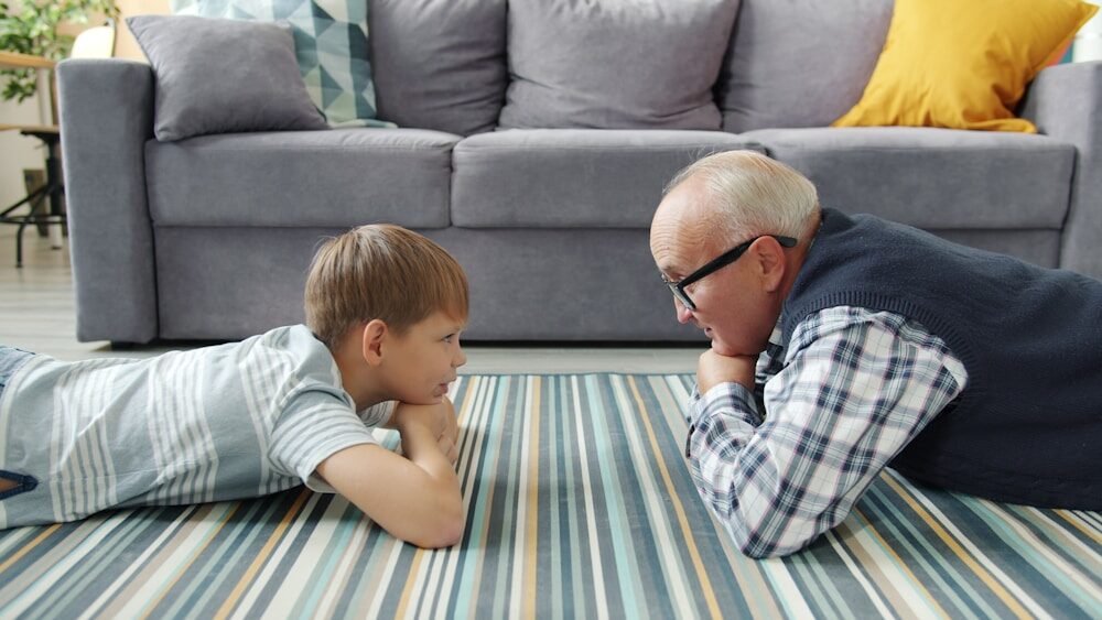 Grandfather and grandson lying on the floor talking