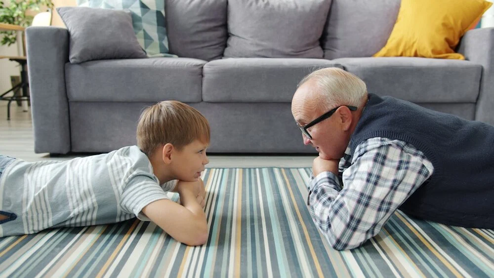 Grandfather and grandson lying on the floor talking
