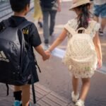 A couple of kids walking down a street holding hands
