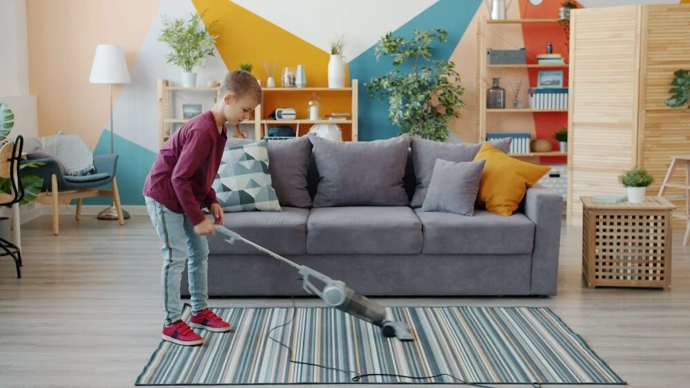 Young girl vacuuming a striped rug in a living room