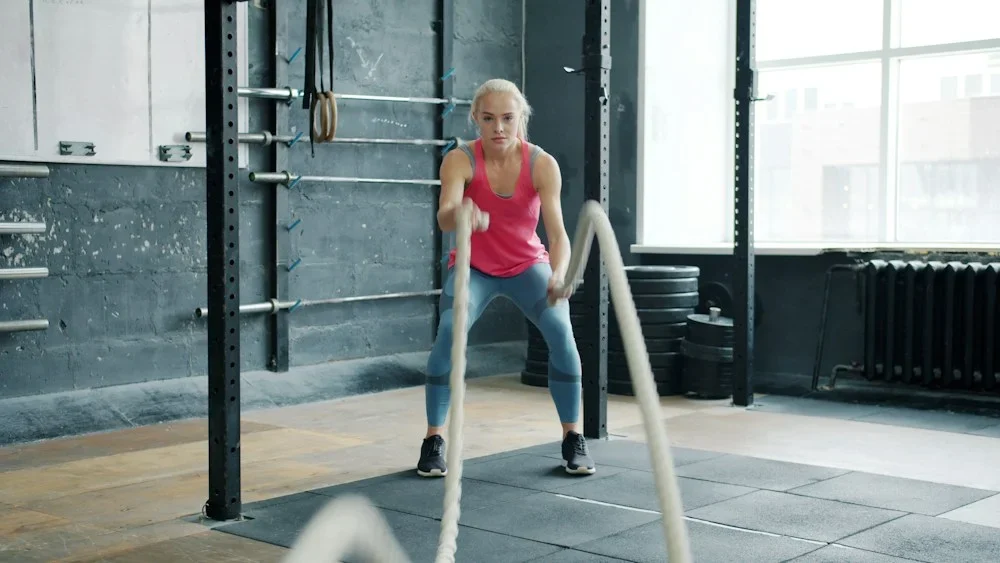 Woman exercising with battle ropes in gym