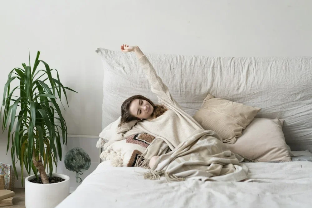a woman laying on a bed with a blanket