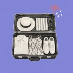 Illustration of an open suitcase packed with summer clothes beside a coral umbrella